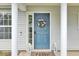 A welcoming blue front door is adorned with a wreath and flanked by decorative lanterns and fluted white pillars at 318 Seneca River Dr, Summerville, SC 29485