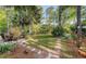 Lush backyard with mature trees, stone pathway, garden, and charming seating areas at 347 Prestwick Ct, Summerville, SC 29483