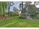 Spacious backyard with lush lawn, mature trees, and view to a golf course at 347 Prestwick Ct, Summerville, SC 29483