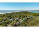 Aerial view of the neighborhood, showcasing a home nestled among lush trees with a distant view of the water at 409 W Indian Ave, Folly Beach, SC 29439