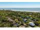 Aerial view of the neighborhood, showcasing a home nestled among lush trees with a view of the beach and pier at 409 W Indian Ave, Folly Beach, SC 29439