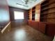 Office with custom built-in wooden shelves and cabinets along one wall, with hardwood floor and natural light at 411 Navaho Cir, Summerville, SC 29483