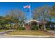 Community entrance featuring signage, landscaping, and an American flag, surrounded by mature trees at 4407 Wild Thicket Ln, North Charleston, SC 29420