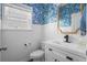 Charming half bath featuring blue wallpaper, wainscoting, a white vanity, black hardware, and a gold mirror at 476 Foxbank Plantation Blvd, Moncks Corner, SC 29461