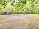 Large open space with light colored gravel ground, an outdoor structure, trees, and foliage in the backyard at 620 Coral Acres Dr, Moncks Corner, SC 29461
