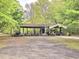 Exterior shot of a two section garage full of tools and equipment surrounded by trees at 620 Coral Acres Dr, Moncks Corner, SC 29461