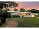 The exterior of the home at dusk is charming with lovely professional landscaping and mature trees at 939 Mikell Dr, Charleston, SC 29412