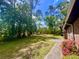 Spacious backyard featuring mature trees, green grass, and a view of the brick home exterior at 1009 Highland Pines Rd, Ladson, SC 29456