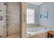 Bathroom with a tile shower, and a luxurious soaking tub under a bright window at 114 W Arctic Ave # B302, Folly Beach, SC 29439