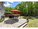 Well-maintained backyard deck featuring a dining set, grill, and vibrant red umbrella for outdoor relaxation and entertaining at 1233 Updyke Dr, Johns Island, SC 29455
