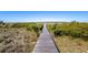 Picturesque wooden boardwalk through sandy dunes and vibrant coastal vegetation towards the ocean at 1342 Pelican Watch Villas, Seabrook Island, SC 29455