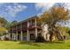 A raised home featuring an expansive screened porch, situated on a lush green lawn at 1392 Eden Rd, Awendaw, SC 29429