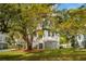 Charming white two-story home with double porches and lush landscaping, nestled under mature trees at 1409 Lieben Rd, Mount Pleasant, SC 29466