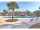Community pool area featuring a palm tree, lounge chairs, and a red-roofed cabana building in the background at 1436 Harbor Mist Ct, Charleston, SC 29492