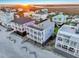 Aerial view showcasing colorful beach homes with decks, ocean access, and stunning sunset at 1681 E Ashley Ave # B, Folly Beach, SC 29439