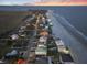 Panoramic aerial view of a coastal community with homes lining a sandy beach and ocean at 1681 E Ashley Ave # B, Folly Beach, SC 29439