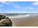 Beautiful ocean view with beach featuring rocks and soft waves under a blue sky with clouds at 1681 E Ashley Ave # B, Folly Beach, SC 29439