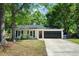 Charming single-story home featuring a red front door, gray garage door, and mature trees at 1812 Overrun St, Charleston, SC 29414