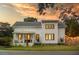 Inviting two-story home with white siding and a cozy front porch basking under a beautiful sunset at 2 Live Oak Ave, Charleston, SC 29407