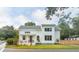 Charming two-story white home with black trim and a welcoming front porch nestled among trees at 2 Live Oak Ave, Charleston, SC 29407