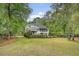 Backyard view of home with a large, green lawn, bordered by trees and a black metal fence at 2037 Shell Ring Cir, Mount Pleasant, SC 29466
