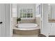 Bright bathroom with a modern soaking tub under a window with white plantation shutters and neutral tile surround at 2104 Royal Pine Dr, Seabrook Island, SC 29455