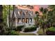 Charming two-story home with inviting front porch, landscaped yard, mature palm trees, and colorful sunset backdrop at 2104 Royal Pine Dr, Seabrook Island, SC 29455