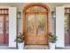Elegant wooden double doors with glass panels, sidelights, and arched transom window, flanked by stylish outdoor lanterns at 2104 Royal Pine Dr, Seabrook Island, SC 29455