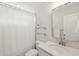 Bright white bathroom featuring shower with white curtain and vanity with quartz counters and clear glass shelving at 217 7Th Ave, Mount Pleasant, SC 29464