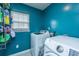 Laundry room featuring side-by-side washing machines with storage shelves and blue walls at 3033 Kinswood Ln, Ladson, SC 29456