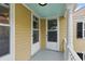 Exterior side porch of a yellow house with light blue ceilings and white columns at 44 Savage St, Charleston, SC 29401