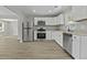 Open kitchen featuring stainless appliances, white cabinets, granite counters, and wood-style flooring at 4432 Logwood Drive, Ladson, SC 29456