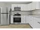Close up of kitchen featuring stainless appliances, white cabinets, granite counters, and wood-style flooring at 4432 Logwood Drive, Ladson, SC 29456