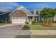 Charming home featuring stone accents, a two-car garage, manicured lawn, and a neatly landscaped front yard at 5049 Song Sparrow Way, Summerville, SC 29483