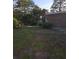 Grassy backyard with mature landscaping and partial view of the side of the brick house at 5937 Willard Dr, Hanahan, SC 29410