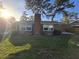 Exterior of a brick home showcasing a chimney, sunny backyard, and mature trees at 5937 Willard Dr, Hanahan, SC 29410