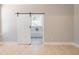 Bright primary bedroom with wood floors and a modern sliding barn door to the bathroom at 74 Longleaf Dr, Walterboro, SC 29488
