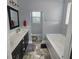 Bathroom featuring a soaking tub, double vanity with dark cabinets, and a window over the toilet at 7406 Purser Ln, Hanahan, SC 29410