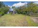 A serene backyard with lush lawn, trees, and charming home with a screened porch at 8551 Pope Landing Rd, Edisto Island, SC 29438