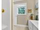 Neutral toned bathroom with white vanity, bright lighting, and a window with backyard views at 8551 Pope Landing Rd, Edisto Island, SC 29438