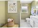 Cozy bathroom with white cabinets, patterned tile floor, seashell decor, and a window at 8551 Pope Landing Rd, Edisto Island, SC 29438