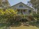 Charming two-story home with a metal roof, inviting front porch and lush landscaping at 8551 Pope Landing Rd, Edisto Island, SC 29438