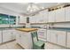 A bright kitchen with white cabinets, teal counters, gas range, and central butcher block island with a green step stool at 8551 Pope Landing Rd, Edisto Island, SC 29438