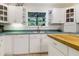 View of the kitchen featuring white cabinets, teal counters, open shelving, and a butcher block island at 8551 Pope Landing Rd, Edisto Island, SC 29438