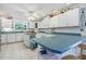 Open kitchen featuring white cabinets, teal counters, a butcher block island, breakfast bar, and white tiled floors at 8551 Pope Landing Rd, Edisto Island, SC 29438