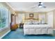 Spacious main bedroom suite featuring blue carpet, a ceiling fan, and bright natural light from the window at 8551 Pope Landing Rd, Edisto Island, SC 29438