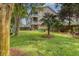 Large, verdant backyard featuring mature trees, green Adirondack chairs, and a wooden fence at 9316 Sweetbay Ct, Ladson, SC 29456