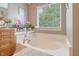 Bright bathroom featuring a soaking tub with tile surround, double sink vanity, and large window at 9316 Sweetbay Ct, Ladson, SC 29456