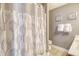 Neutral bathroom with patterned shower curtain, decorative art and ample lighting at 9316 Sweetbay Ct, Ladson, SC 29456