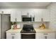 Close-up of the kitchen's stainless steel microwave and black range with white cabinets and subway tile backsplash at 1027 Island View Ct, Charleston, SC 29492
